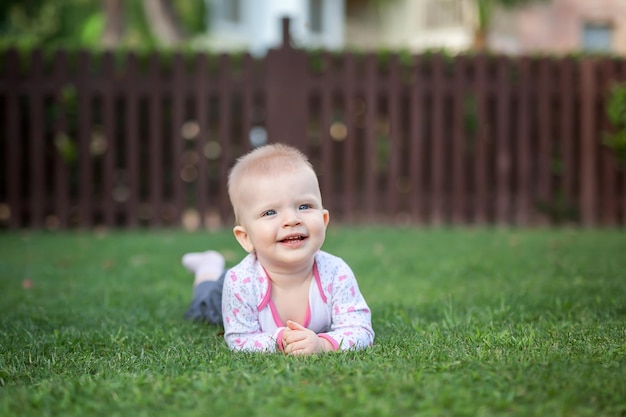 Un petit enfant se trouve sur l'herbe et sourit