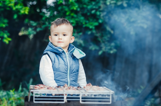 Un petit enfant sur son propre barbecue sur le gril aide