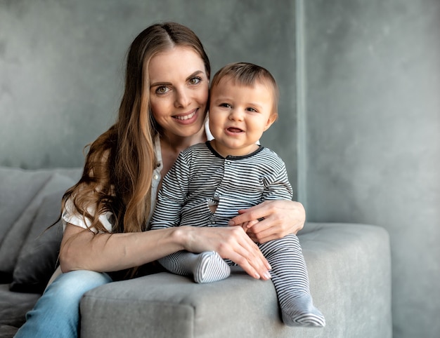 Petit enfant souriant et heureux avec maman sur le canapé