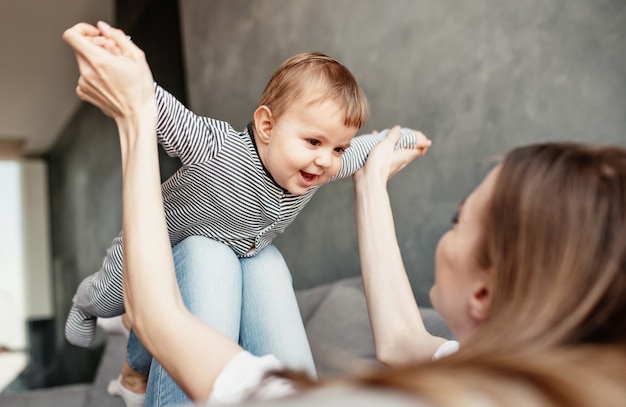 Petit enfant souriant et heureux avec maman sur le canapé