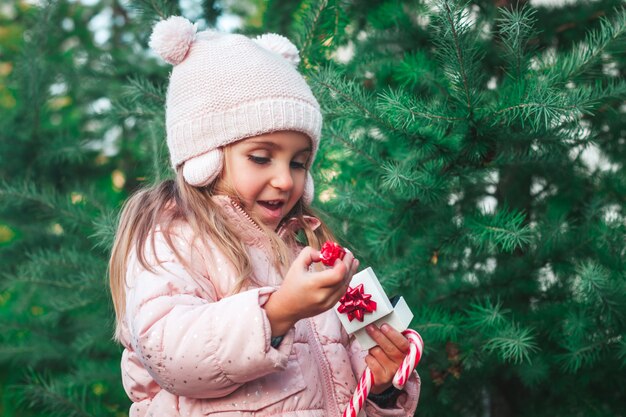 Un petit enfant surpris se réjouit ouvre un cadeau dans le parc Noël