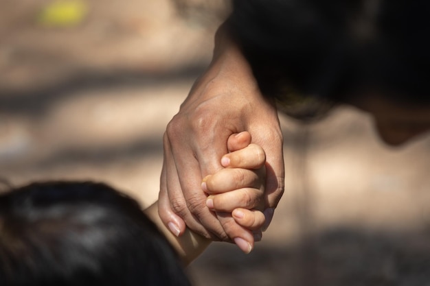 Petit enfant tenant la main d'une mère membre de la famille comme une famille unie