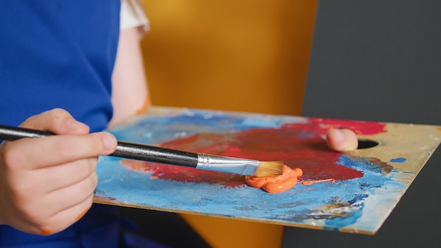 Petit enfant tenant un plateau de mélange d'aquarelle avec de la couleur de peinture, utilisant un pinceau et une palette d'aquarelle pour créer un chef-d'œuvre d'art humide. Petite fille apprenant à peindre avec des compétences créatives. Fermer.