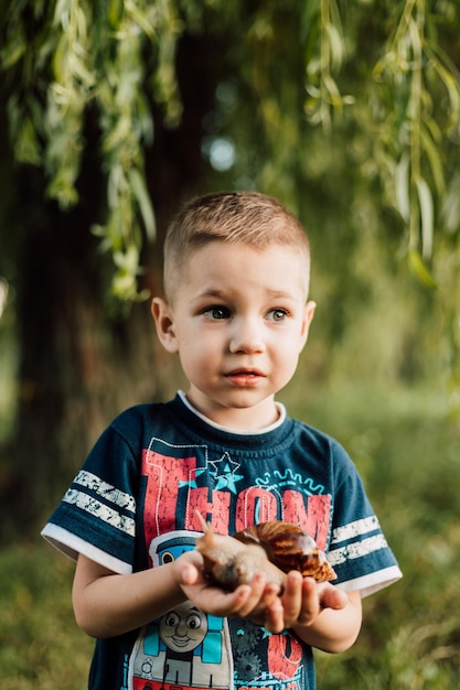 Un petit enfant tient des jouets dans ses mains et surpris dans la nature sous un arbre