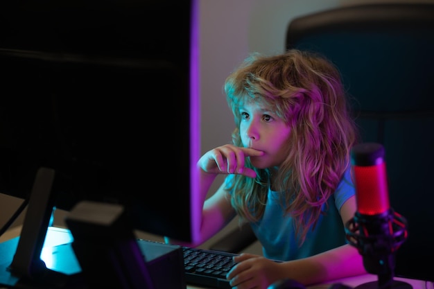 Petit enfant utilisant un ordinateur de bureau la nuit enfant garçon éclairé par la lumière bleue d'un écran d'ordinateur Gamer jouer à un jeu d'ordinateur de bureau Concept d'éducation à distance Apprentissage en ligne pour enfants