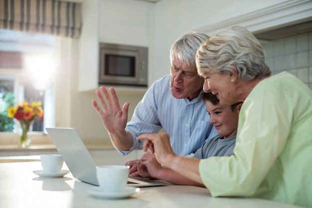 Petit-fils à l'aide d'un ordinateur portable avec des grands-parents