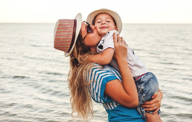 petit fils dans ses bras, embrasse maman au bord de la mer