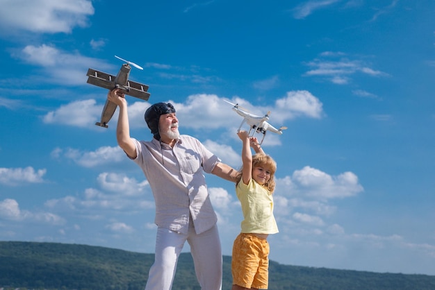 Petit-fils enfant et grand-père avec avion et drone quadcopter sur fond bleu ciel et nuages