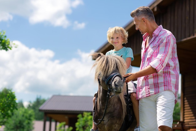 Petit fils se sentant heureux à cheval pour la première fois