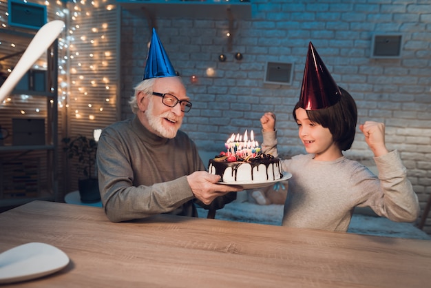 Petit-fils soufflant des bougies sur le gâteau d'anniversaire