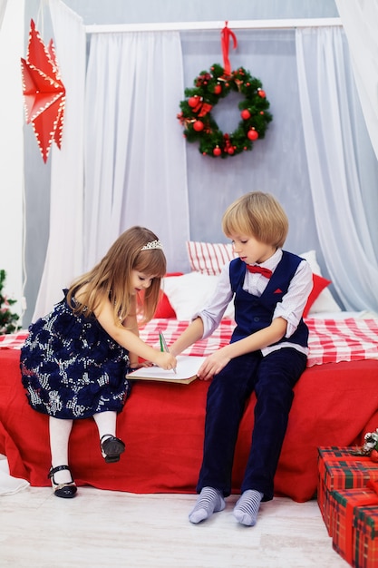 Petit frère et soeur écrivant une lettre au père Noël.