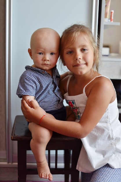 Photo le petit frère avec la soeur à la maison s'embrassent