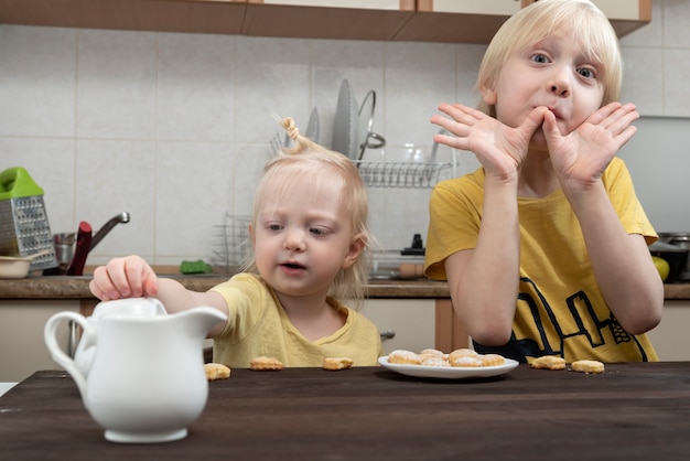 Petit frère et soeur prennent le petit déjeuner dans la cuisine