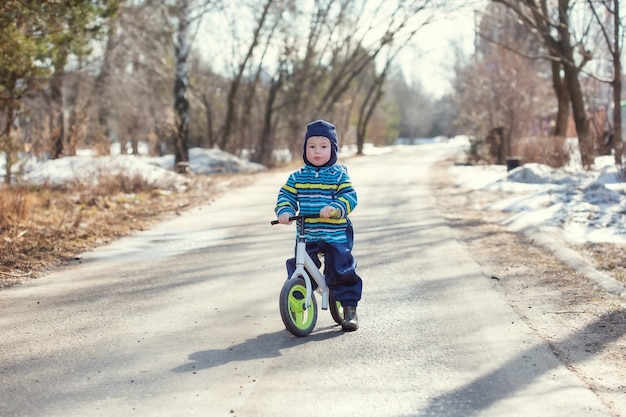 Un petit garçon de 2 ans apprend à faire du vélo d'équilibre sur la route du village