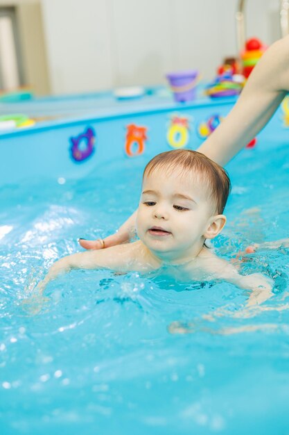 Un petit garçon de 2 ans apprend à nager dans une piscine avec un coach Cours de natation pour enfants