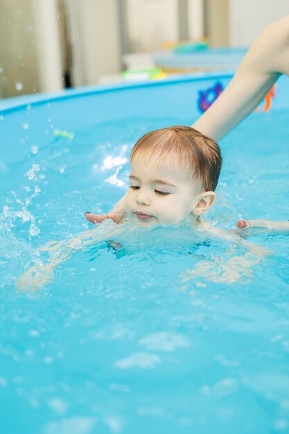 Un petit garçon de 2 ans apprend à nager dans une piscine avec un coach Cours de natation pour enfants