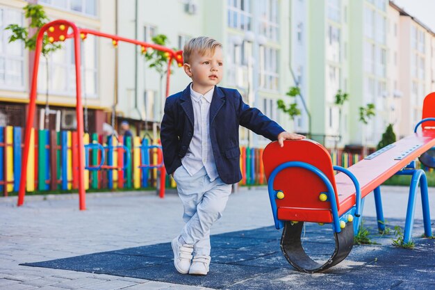 Un petit garçon de 2 ans vêtu d'une chemise et d'une veste se tient dans la rue Costume classique pour enfants pour les vacances Mode enfantine