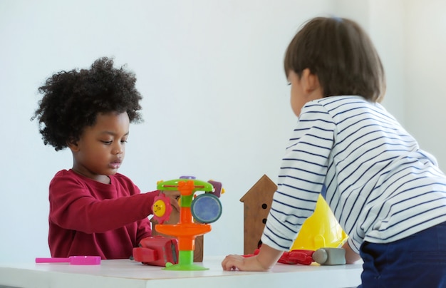 Petit garçon adorable jouant avec un ami à l'école. Concept afro-américain et amis.