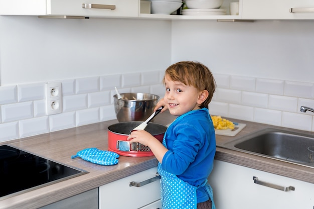 Petit garçon adorable petit garçon portant un tablier de cuisine cuisson tarte domestique aux pommes