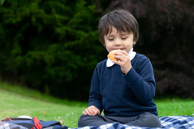 Petit garçon affamé mangeant des tortillas fraîches avec du poulet, du bacon et des légumes mélangés, mignon écolier implantant un pique-nique dans le parc, enfant mangeant des sandwichs mexicains pour son dîner