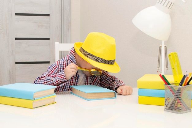 Un petit garçon d'âge préscolaire au chapeau jaune tient un livre dans ses mains. l'enfant s'intéresse aux livres. Mise au point sélective.