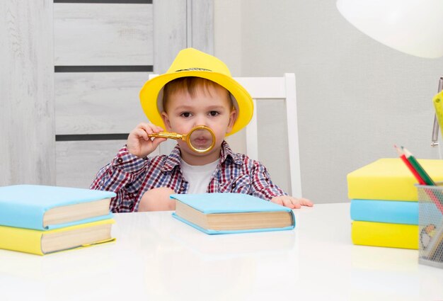 Un petit garçon d'âge préscolaire au chapeau jaune tient un livre dans ses mains. l'enfant s'intéresse aux livres. Mise au point sélective.