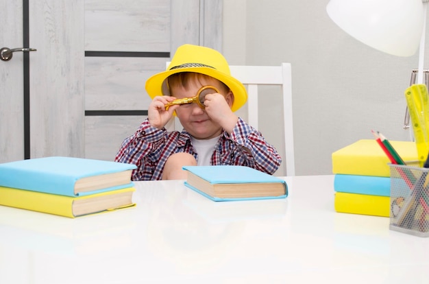 Un petit garçon d'âge préscolaire au chapeau jaune tient un livre dans ses mains. l'enfant s'intéresse aux livres. Mise au point sélective.