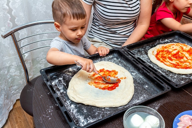 Petit garçon aidant la mère à faire des pizzas à la maison