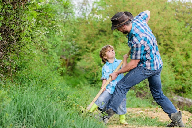 Petit garçon aide père dans l'agriculture. sol naturel riche. Ferme écologique. Ranch. père et fils plantant un arbre généalogique. nouvelle vie. engrais des sols. joyeux Jour de la Terre. Creusez le sol avec une pelle. Plantez en terre.