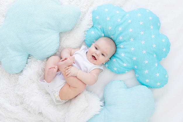 Petit garçon allongé dans son lit avant d'aller au lit, mignon, riant, six mois, souriant petit bébé