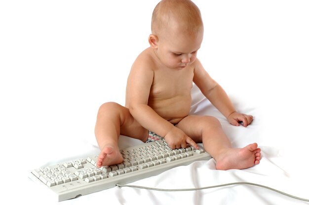 Petit garçon d'un an jouer avec un gros clavier PC sur un fond blanc isolé