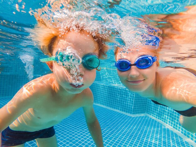 Petit garçon apprenant à nager dans une piscine mère tenant l'enfant