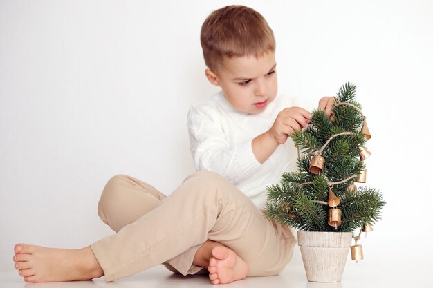 Petit garçon avec arbre de Noël sur fond blanc. Enfant heureux, fête de Noël, temps de Noël.