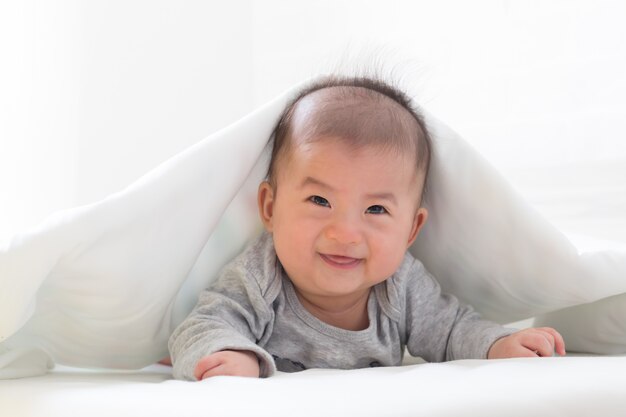 Petit garçon asiatique sourire avec une couverture blanche