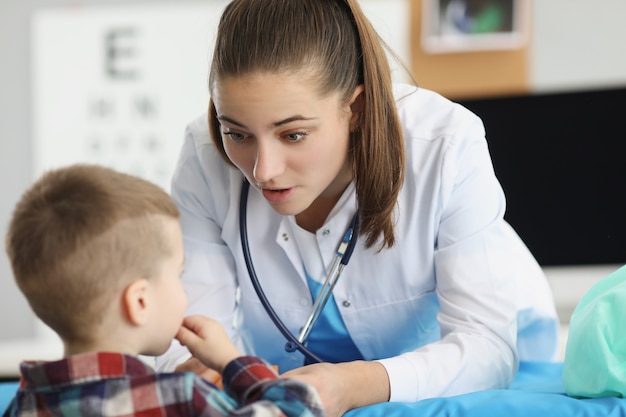 Petit garçon assis au rendez-vous d'une femme pédiatre en clinique