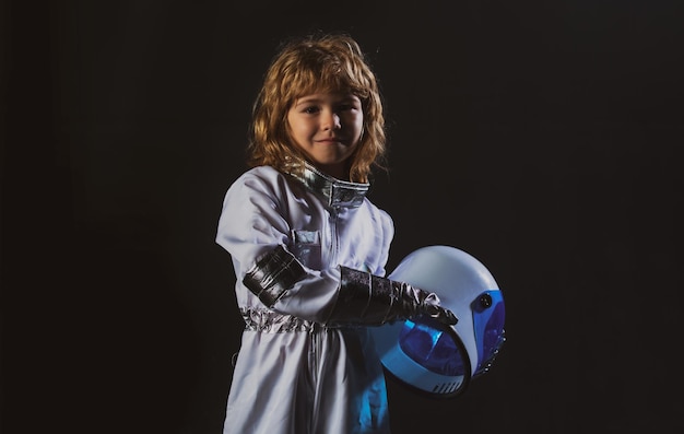 Photo petit garçon astronaute en combinaison spatiale tenant un casque sur fond noir