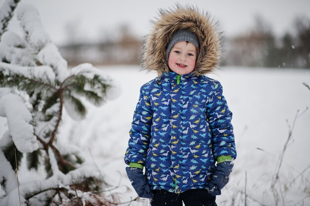 Petit garçon au jour d'hiver. Marcher dans le parc par temps froid avec de la neige.