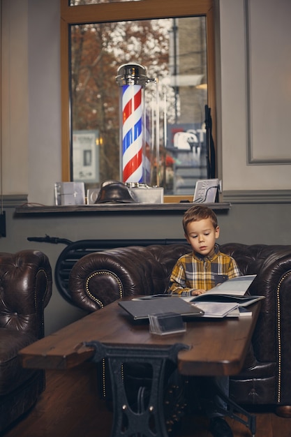 Petit Garçon Au Salon De Coiffure Dans La Salle D'attente En Attente De Maître