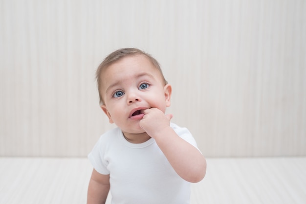 Petit garçon aux yeux bleus sur un fond en bois blanc