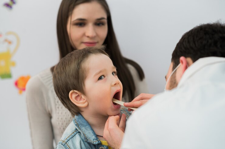 Petit garçon ayant sa gorge examinée par un professionnel de la santé