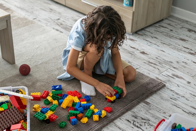 Petit garçon en bas âge jouant avec des blocs de plastique colorés à la maison, construisant un jeu d'imagination créatif