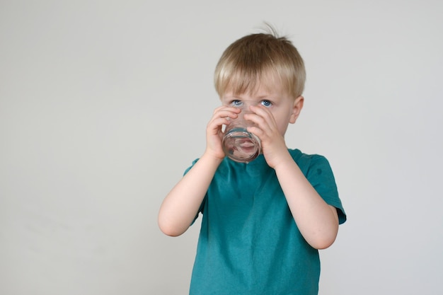 petit garçon blond boit de l'eau