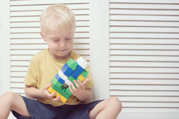 Petit garçon blond joue avec des blocs de couleur