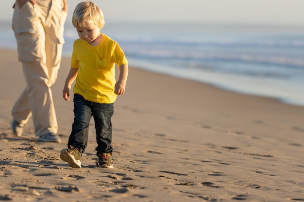 Petit garçon blond marchant sur la côte avec sa mère