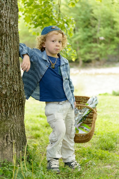 Petit garçon blond avec un panier, à l'extérieur