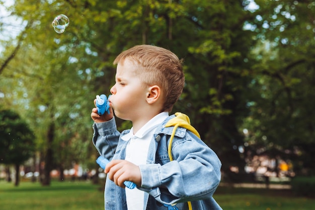 Petit garçon avec des bulles de savon dans le parc journée ensoleillée de printemps jeux actifs pour les enfants