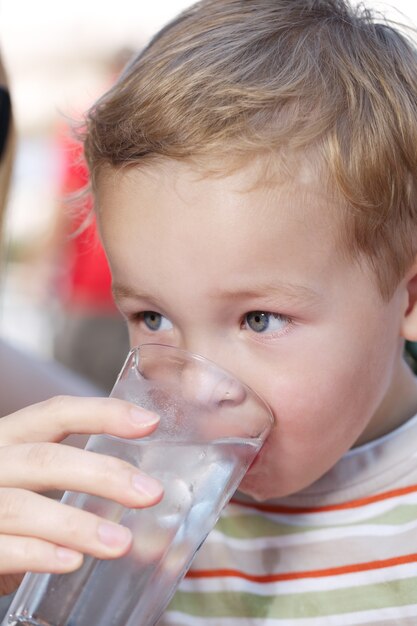 Petit garçon buvant un verre d&#39;eau fraîche