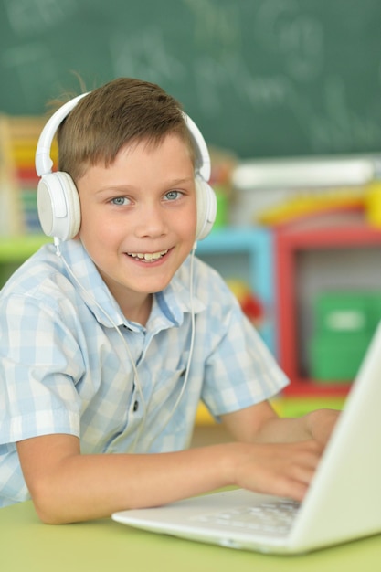 Petit garçon avec un casque à l'aide d'un ordinateur portable en classe