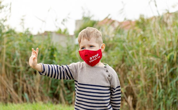 Petit garçon caucasien dans un masque de protection. Un garçon mignon protège la propagation du virus de la maladie avec un masque. COVID-19 [FEMININE. Prévention contre le coronavirus lors d'une pandémie. Soins de santé. protection