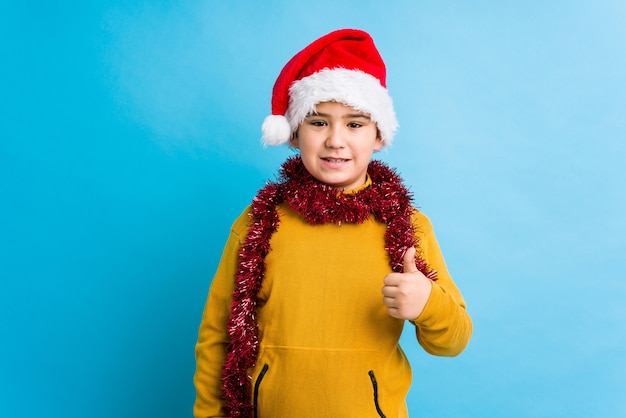 Petit garçon, célébrer, jour noël, porter, a, noël chapeau, isolé, sourire, et, lever pouce, haut